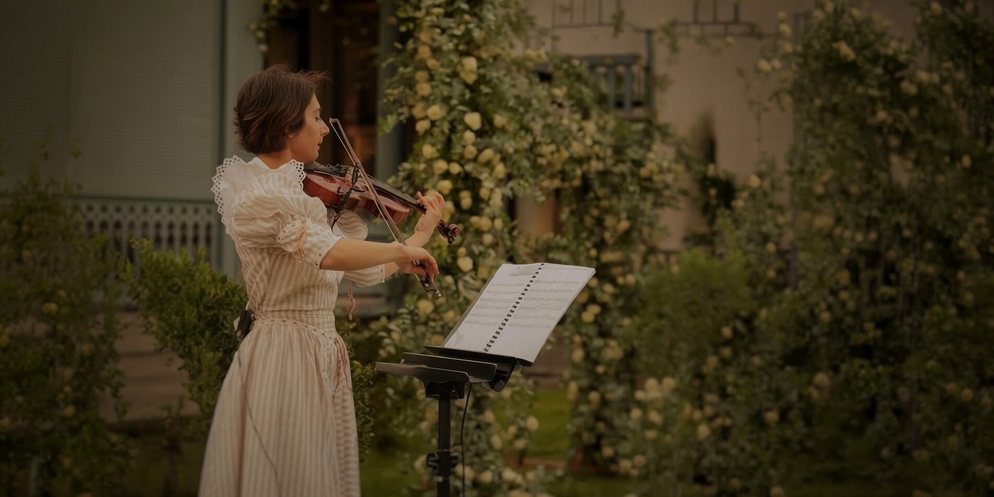 Mariam Makalatia playing violin in a rose garden at dusk
